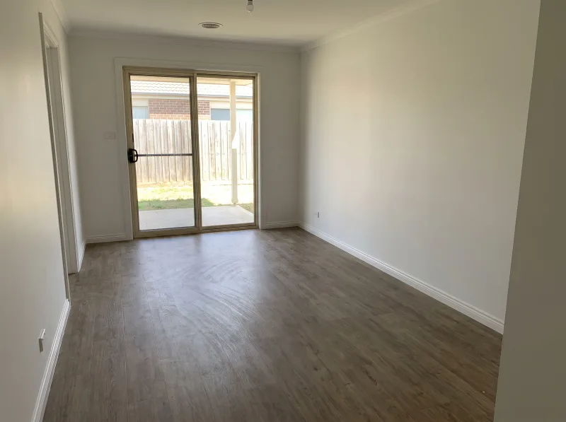 An empty living room with freshly touched-up white walls and clean skirting boards